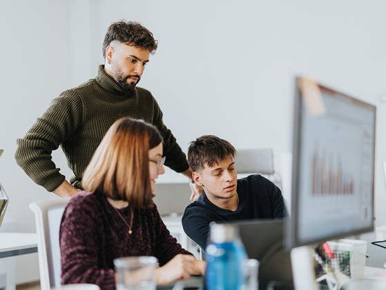 Team members discussing data analytics on screen in modern office environment