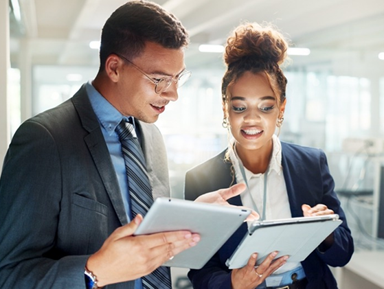 Two corporate professionals reviewing digital billing analytics on tablets