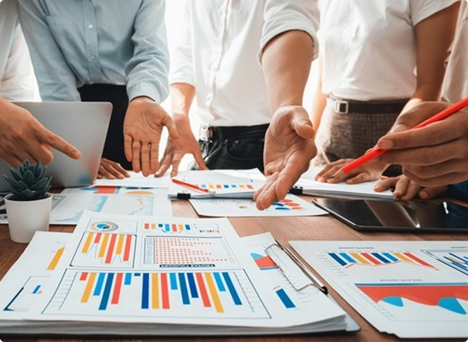 Corporate team working around printed data reports and charts on desk