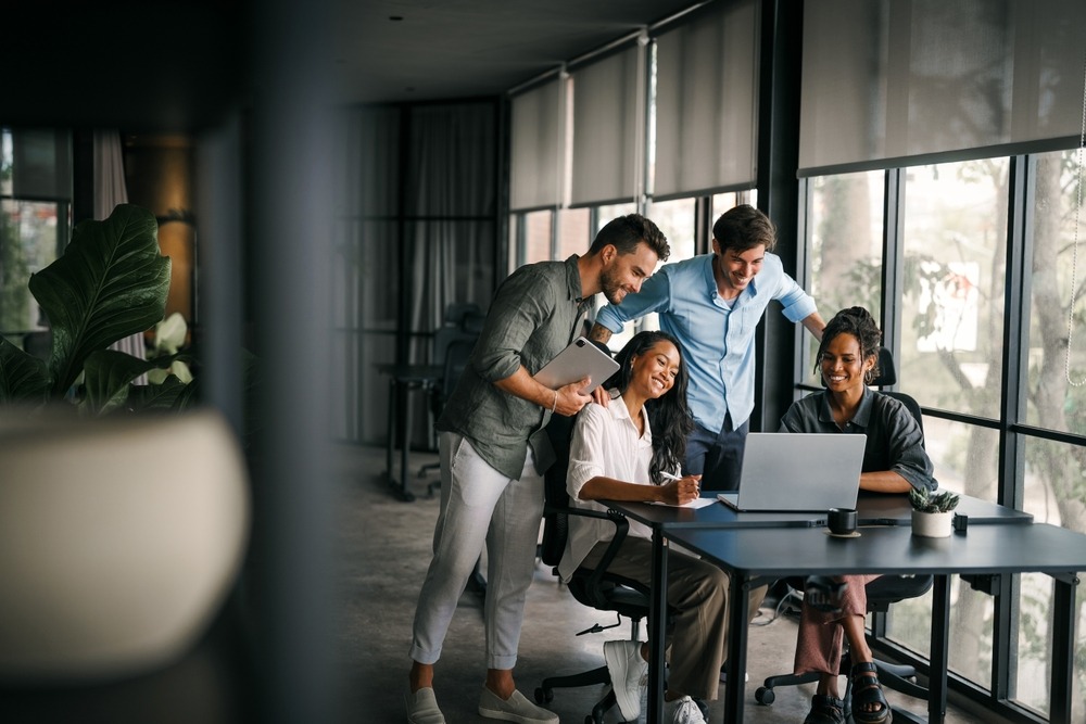 Team of diverse professionals collaborating around laptop