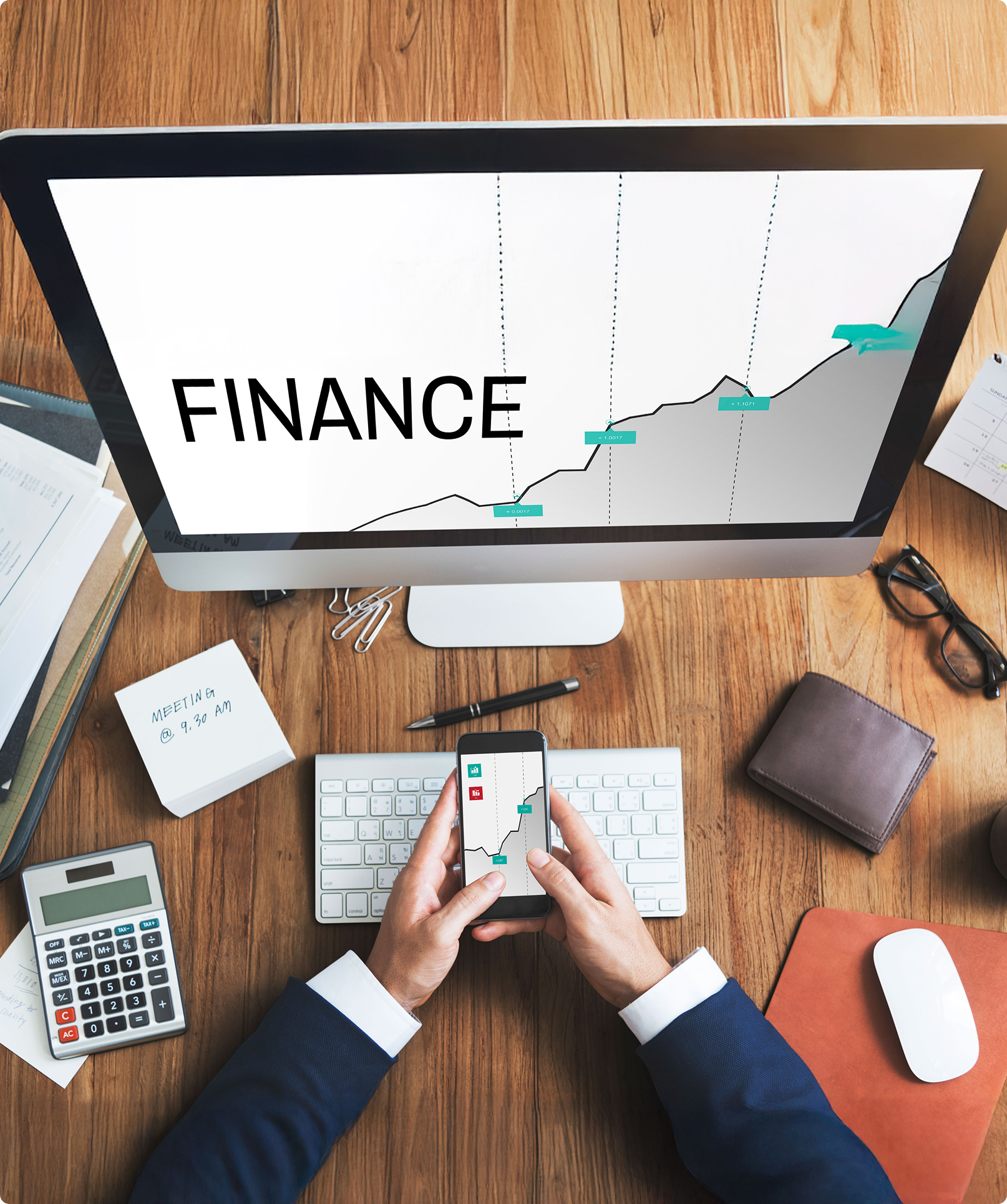 Desktop displaying financial analytics with computer, calculator, and phone on desk