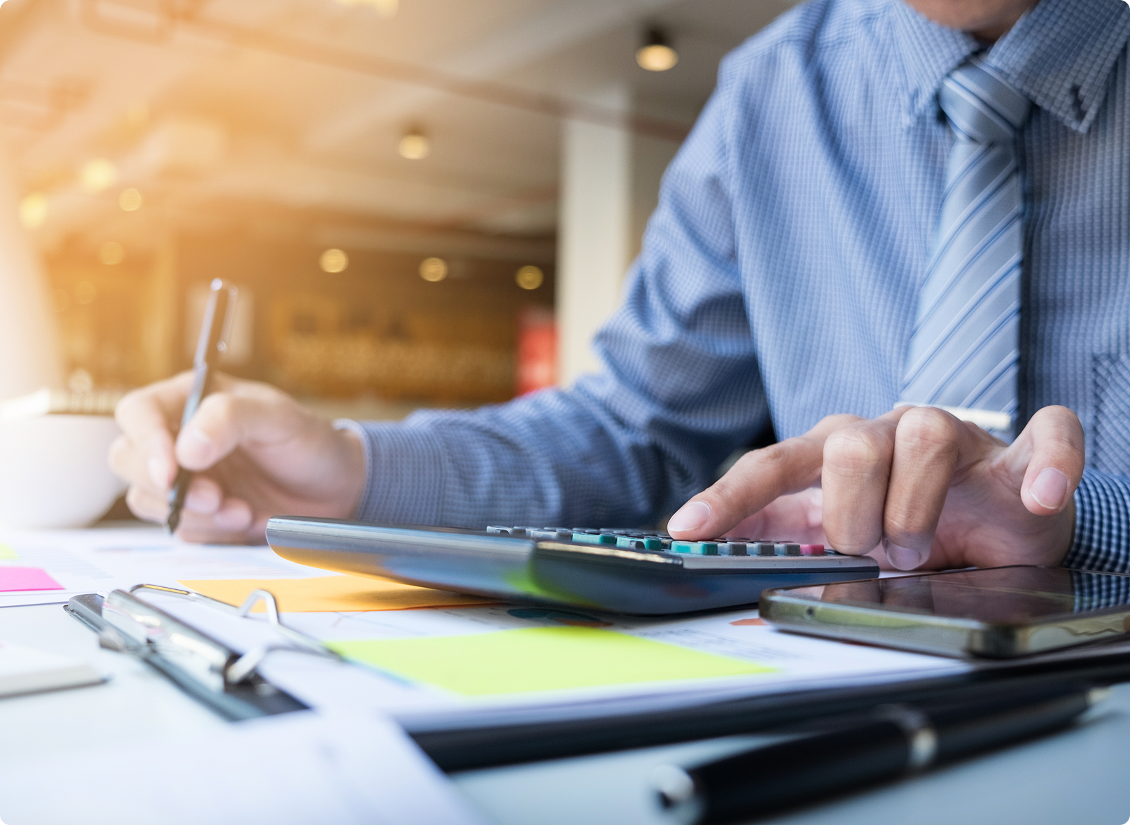 Accountant using a calculator and signing business financial paperwork
