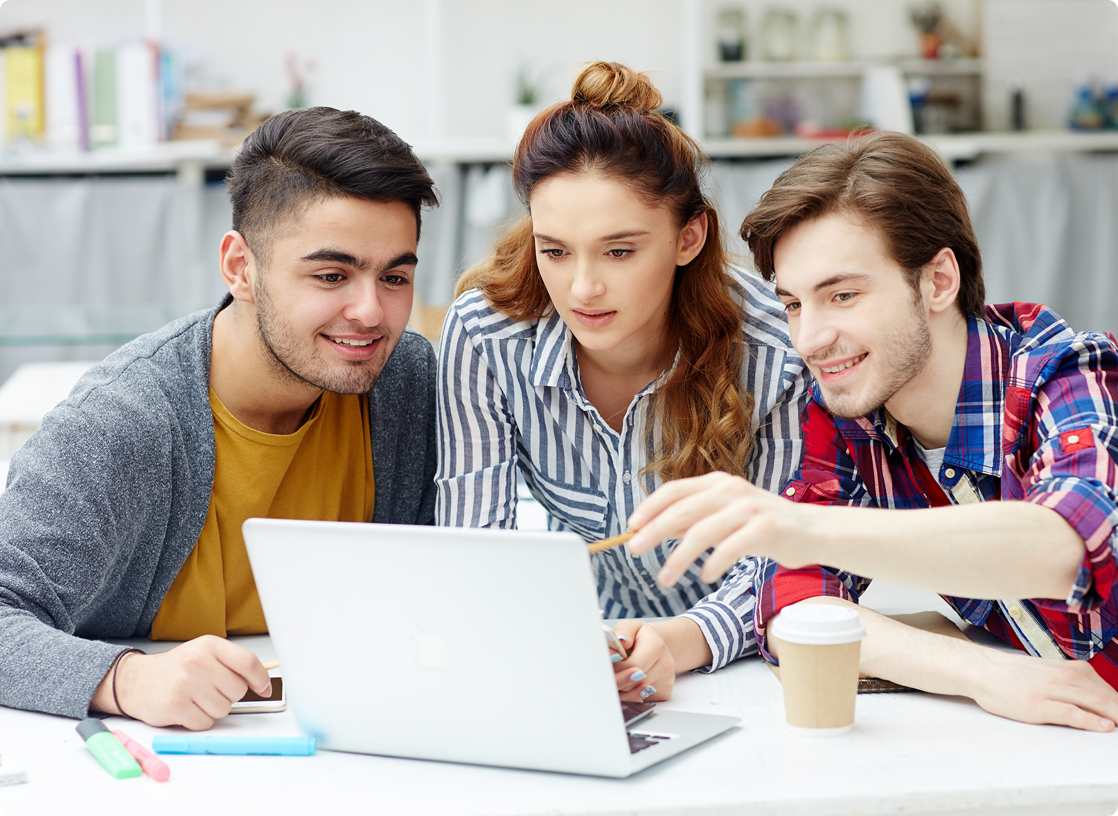 Group of young professionals collaborating over a laptop in a learning environment