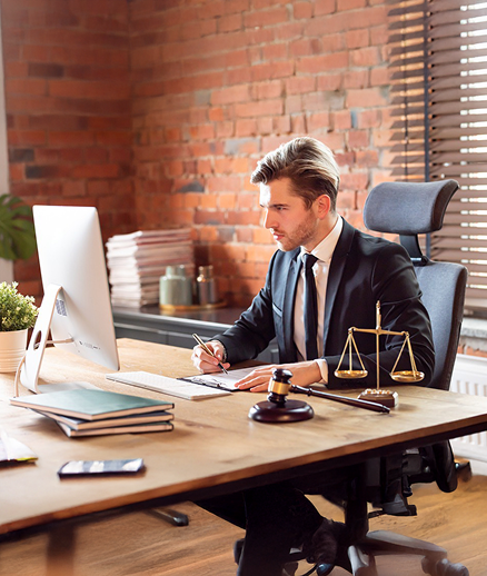 Professional working at desk with laptop and legal scales of justice
