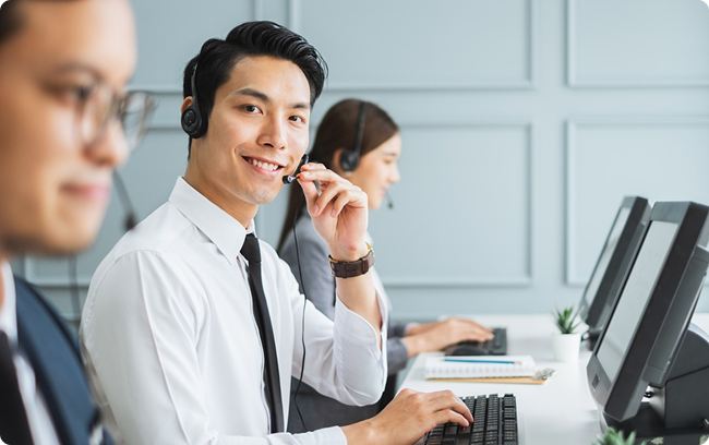 Customer service and telecommunications support agents with headsets working at computer terminals